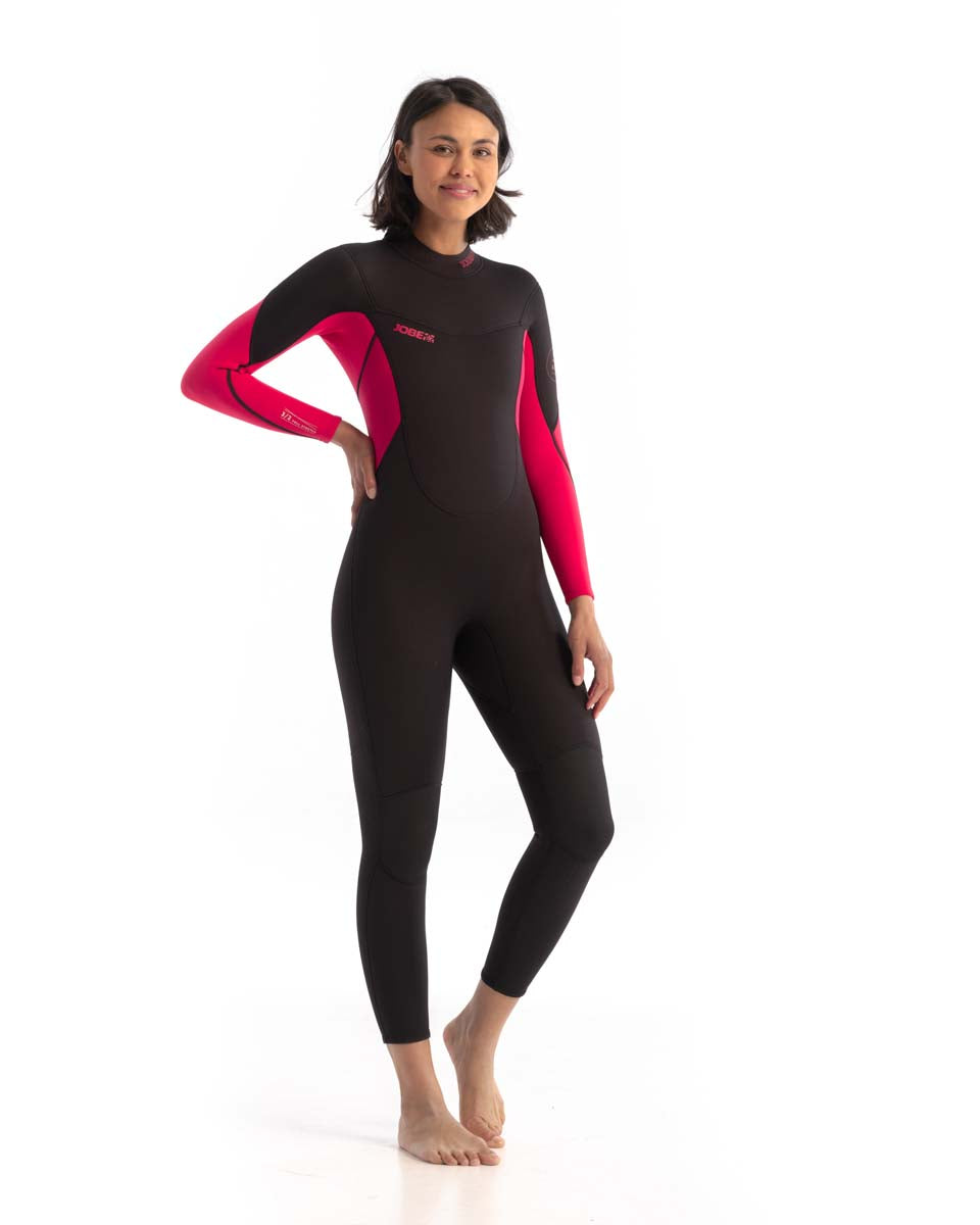 A woman standing, wearing a black and hot pink Jobe Sofia wetsuit with long sleeves and a back full zipper. Front view
