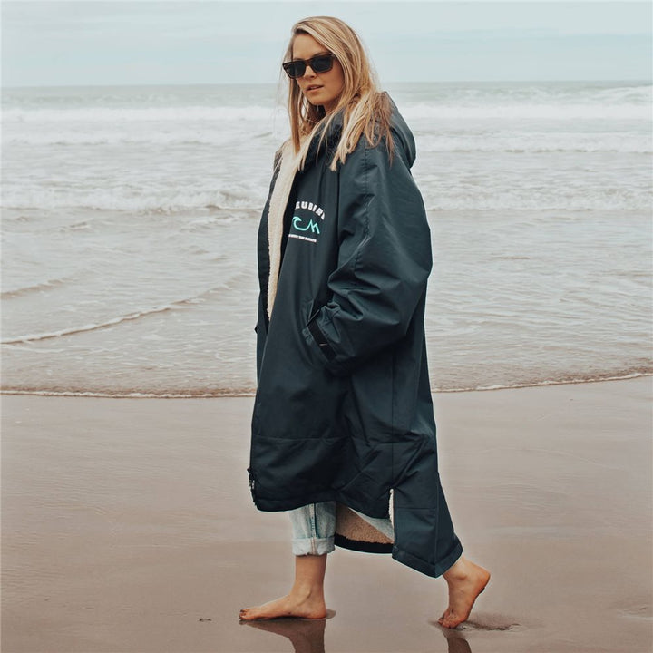 A woman wearing a long-sleeved Bleubird Nordic outdoor changing robe with a hood