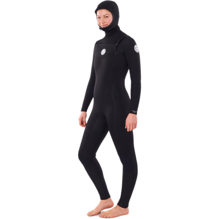 A woman wearing a Rip Curl black hooded chest zip wetsuit, designed for water sports. Side view. 